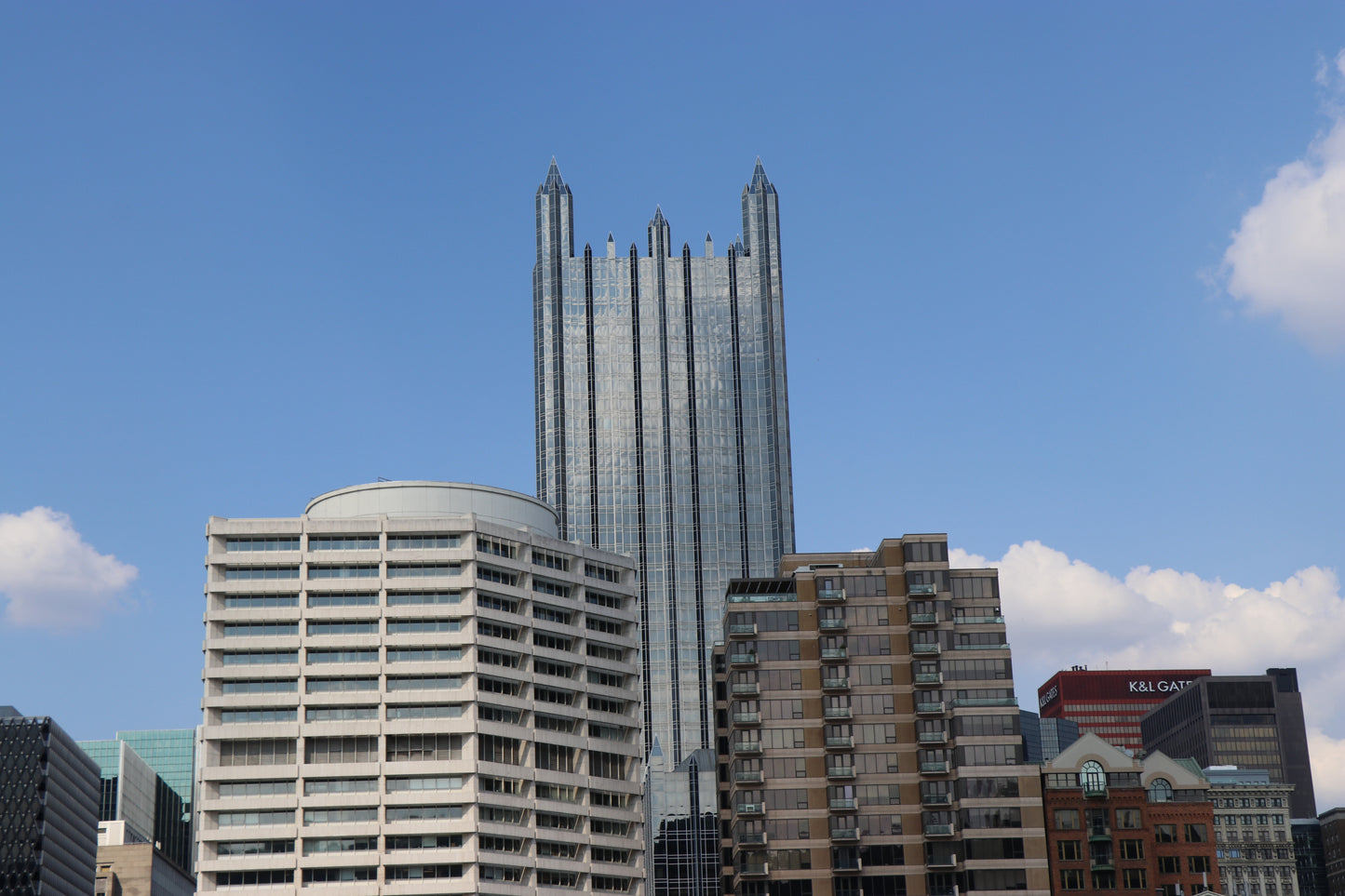 City skyline with a prominent skyscraper against a blue sky with clouds